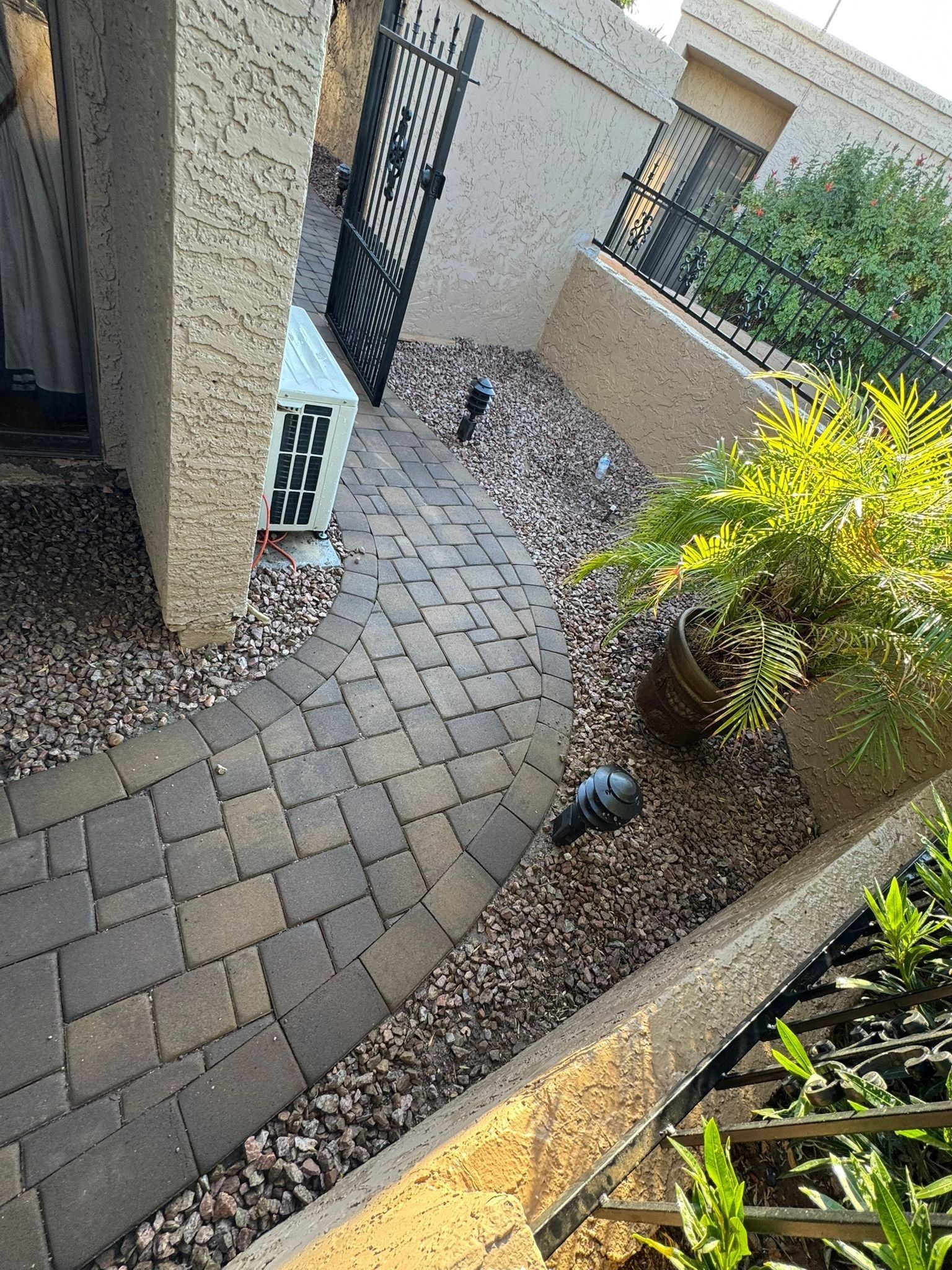 A brick walkway leading to a house with a gate.