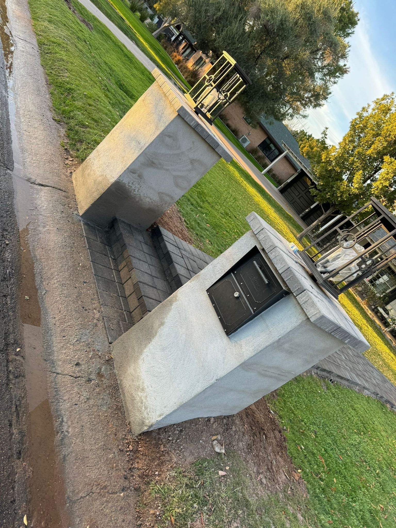 A concrete pillar is sitting on the side of a road next to a park.