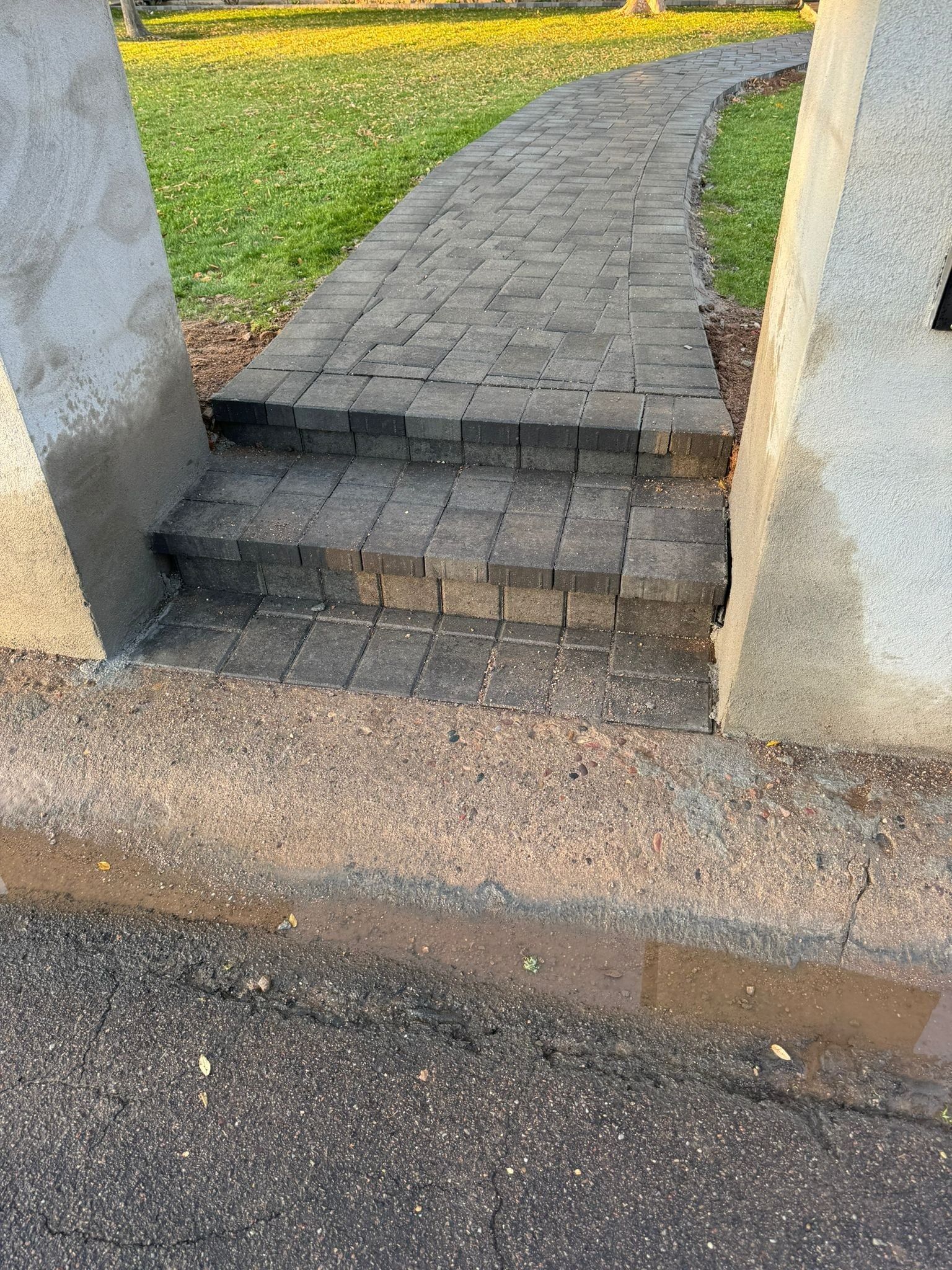 A brick walkway with steps leading up to a grassy area.