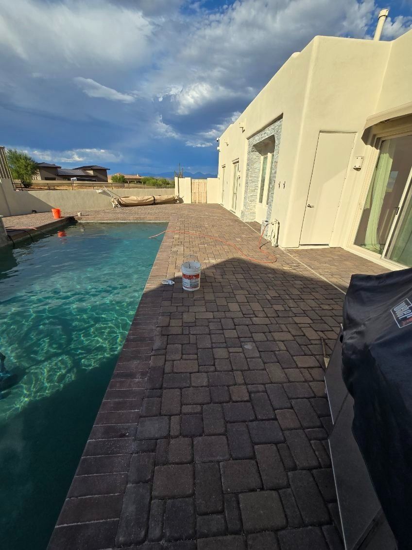 A brick patio with a swimming pool in the background.