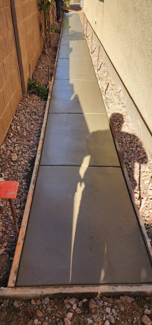 A concrete sidewalk is being built next to a house.