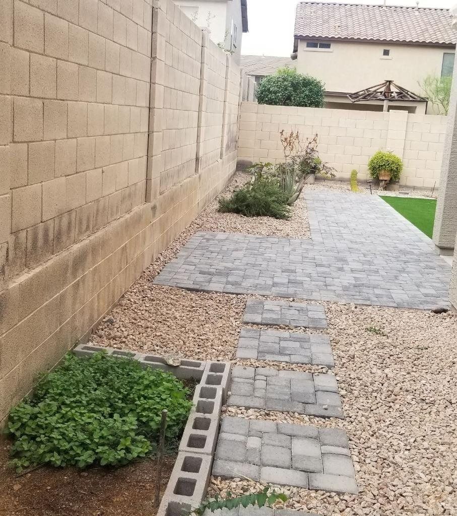 A stone walkway leading to a backyard with a brick wall