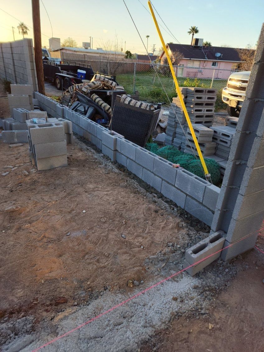 A brick wall is being built in a dirt field.