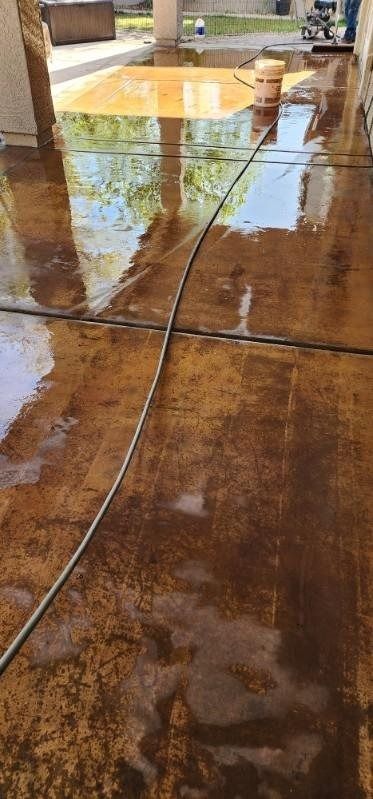 A person is cleaning a concrete floor with a hose.