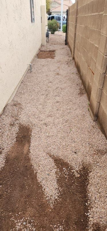 A dirt path leading to a house next to a brick wall.