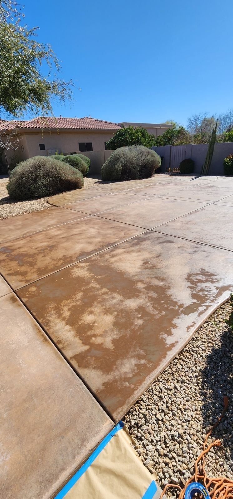 A concrete driveway is being cleaned in front of a house.