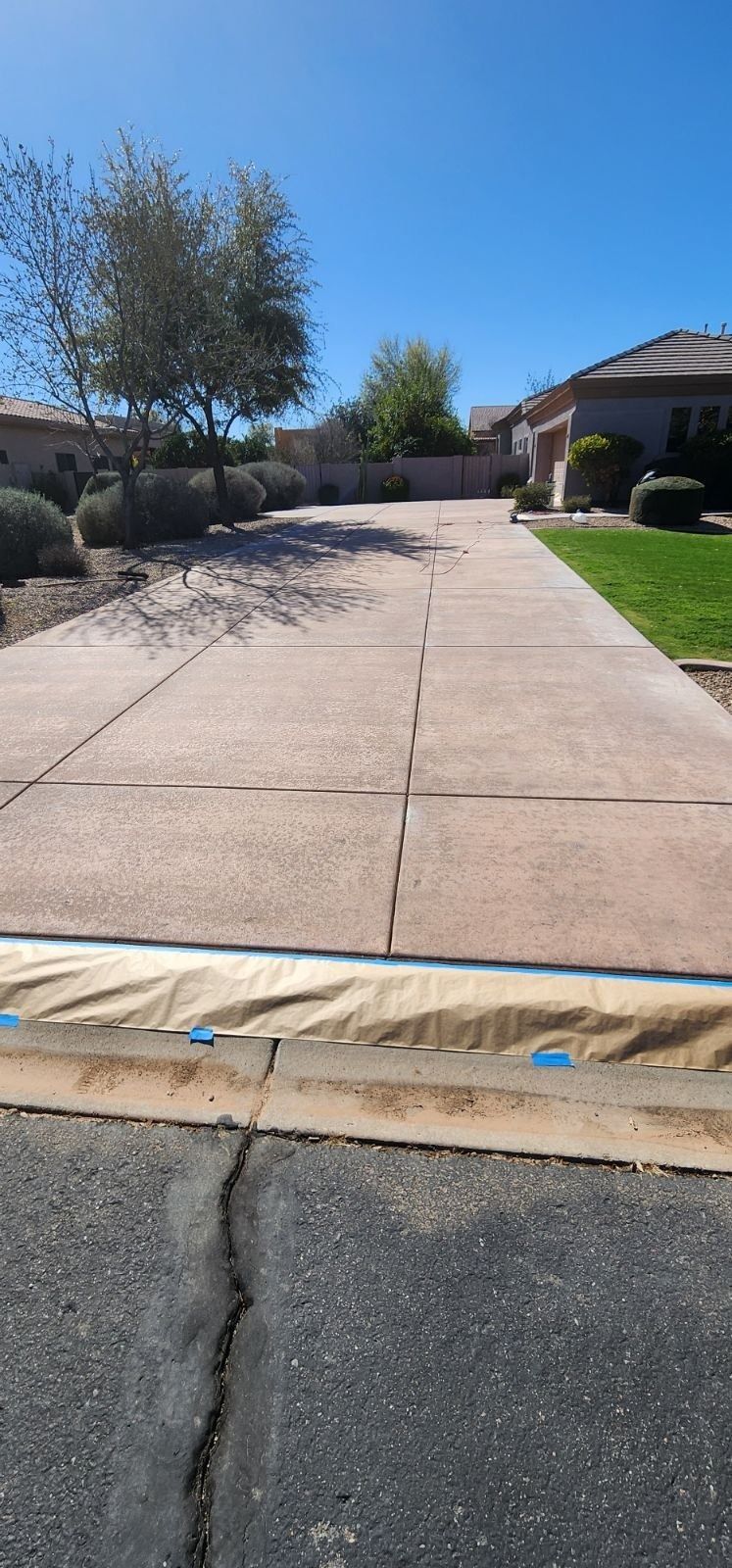 A concrete driveway leading to a house on a sunny day.