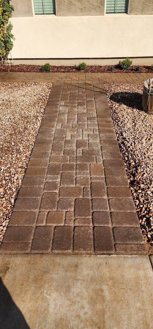 A brick walkway leading to a house surrounded by rocks and gravel.