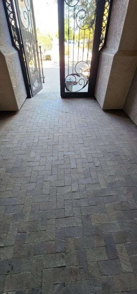 A hallway with a brick floor and a glass door.