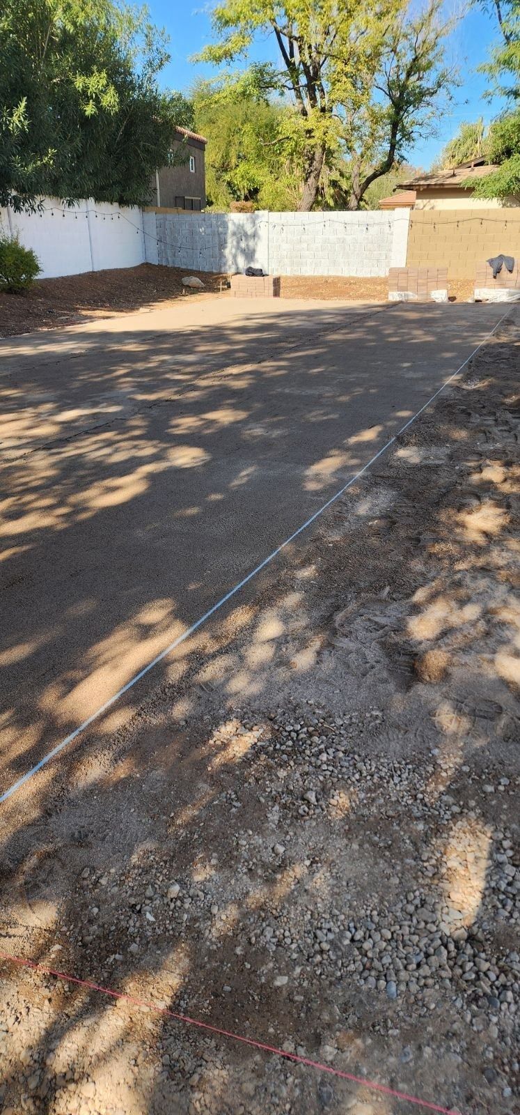 A dirt road with a white fence and trees in the background.