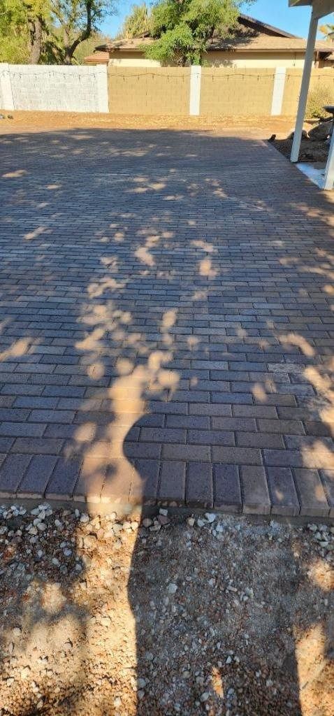 A brick driveway with a shadow of a tree on it.