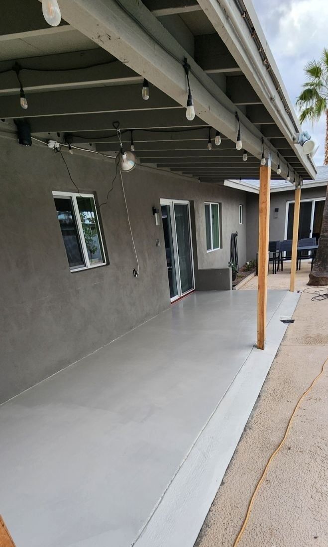 A covered porch with lights hanging from the ceiling of a house.