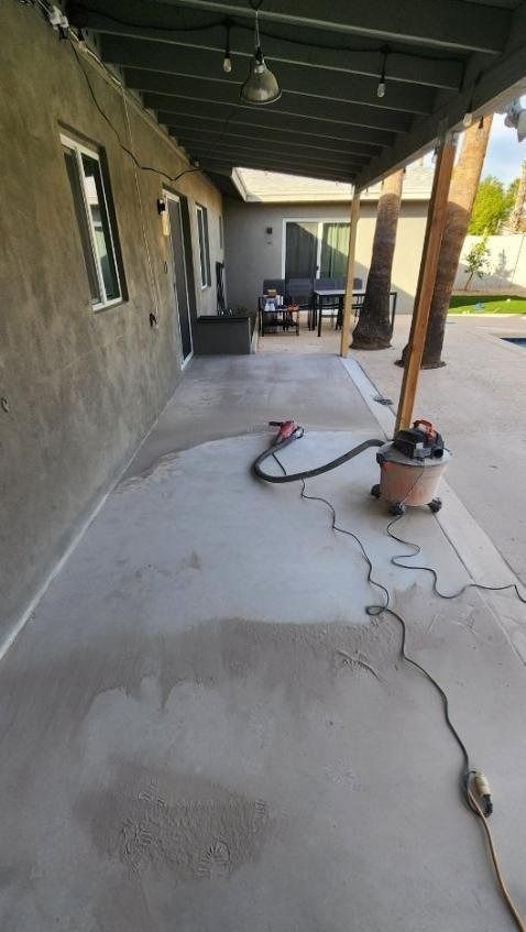 A vacuum cleaner is sitting on a concrete patio next to a house.