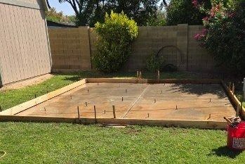 A concrete base is being built in the backyard of a house.