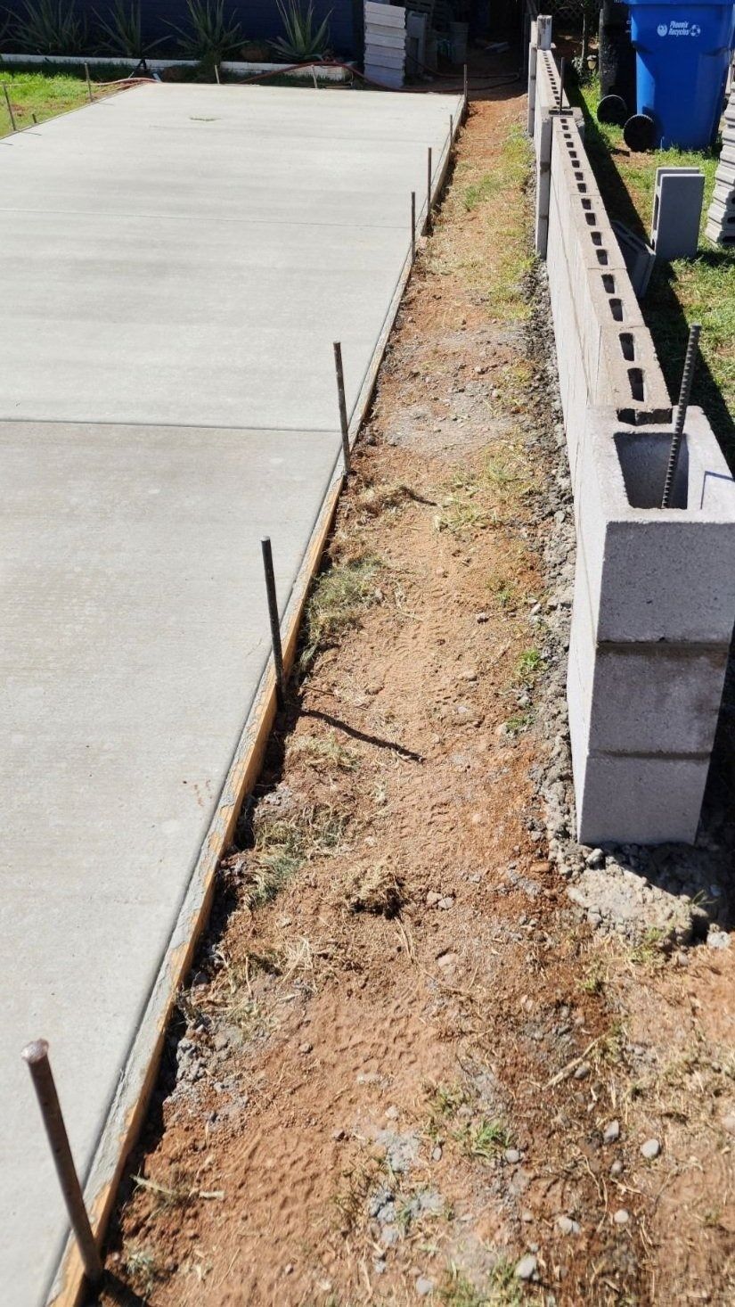 A concrete driveway is being built next to a brick wall.