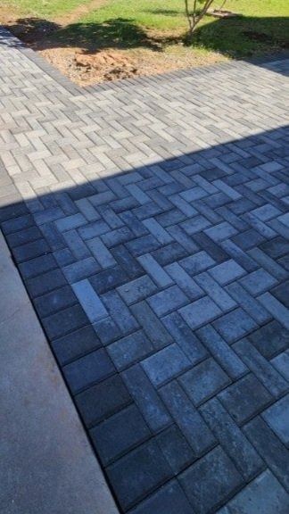 A black and white brick driveway with a grassy area in the background.