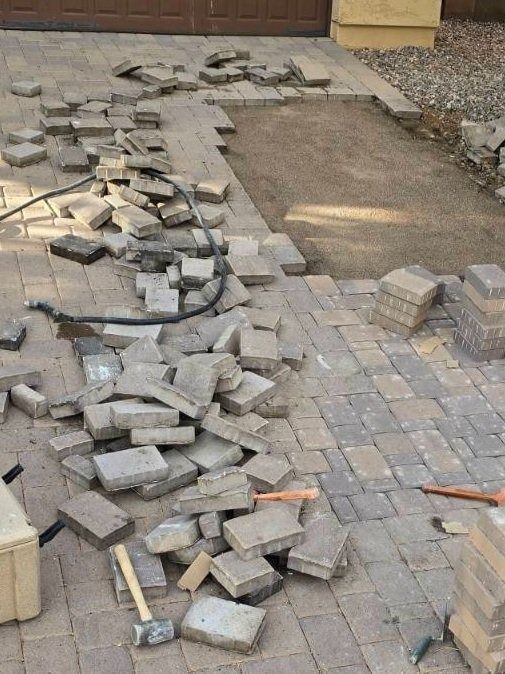 A pile of bricks is laying on the ground in front of a garage door.