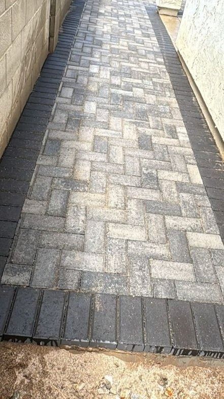 A walkway made of bricks is being built next to a brick wall.