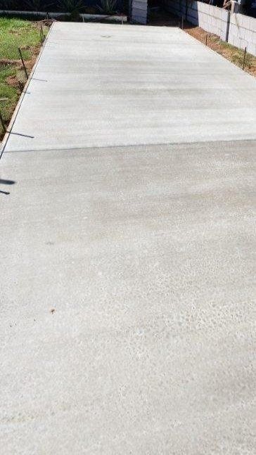 A long concrete driveway leading to a house.