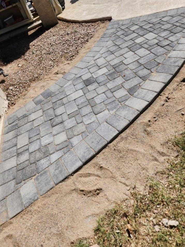 A brick walkway is being built in the dirt.