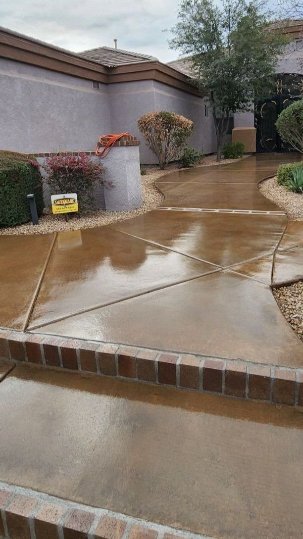 A wet concrete driveway in front of a house.
