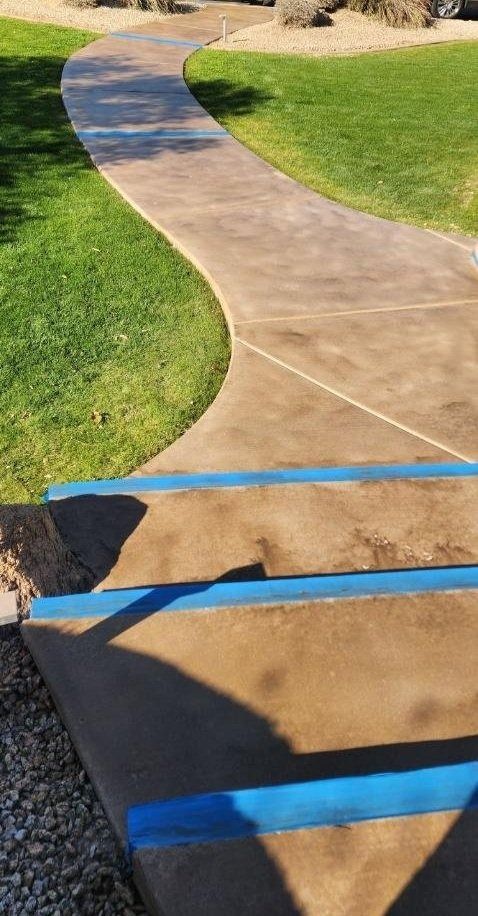 A concrete walkway going through a lush green field.
