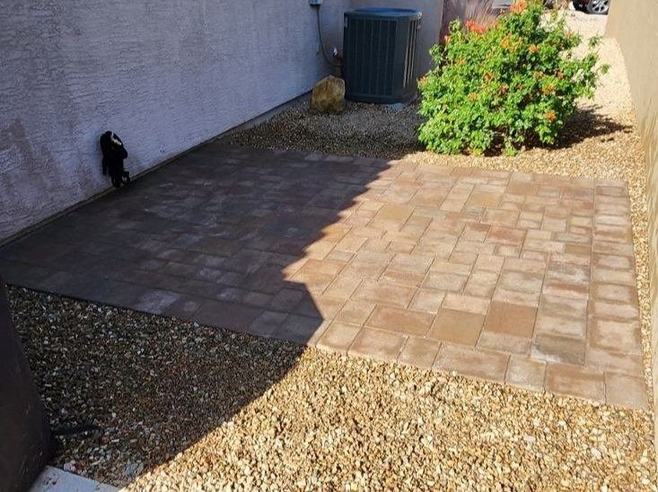 A patio with bricks and gravel in front of a building