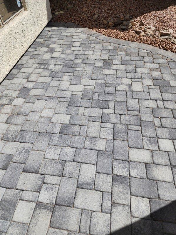 A brick walkway with a house in the background
