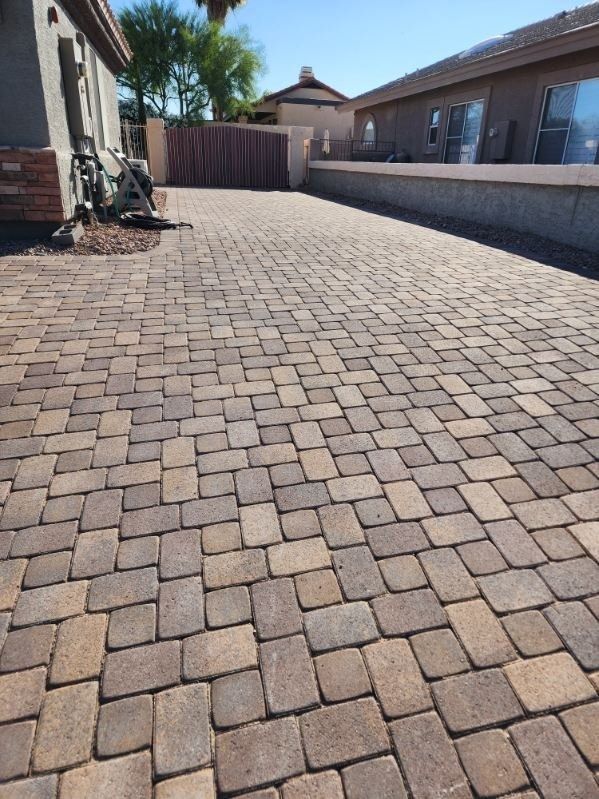 A brick driveway with a house in the background