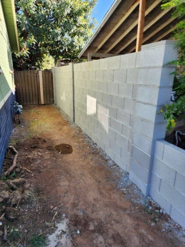 A brick wall is being built in the backyard of a house.