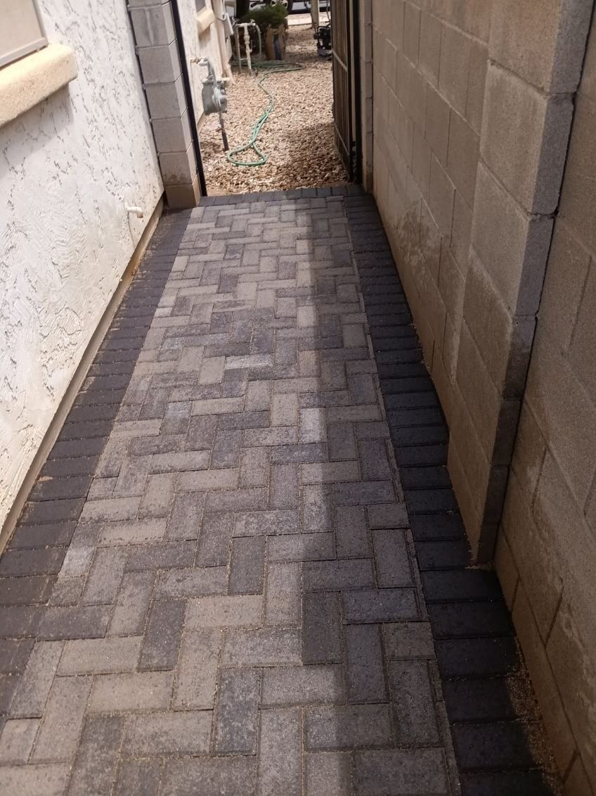 A brick walkway leading to a doorway next to a brick wall.