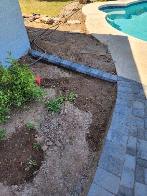 A brick walkway is being built next to a pool.