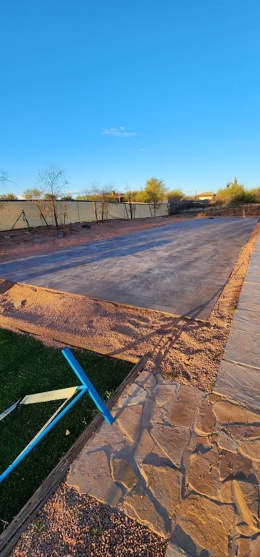 A blue rake is sitting on the side of a dirt road.