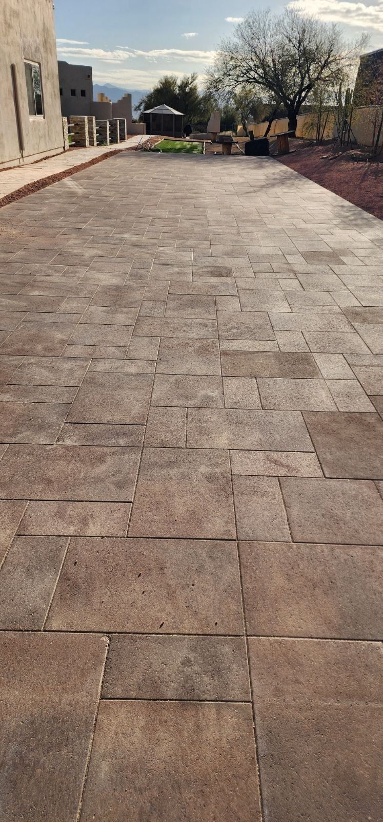 A brick walkway leading to a building with trees in the background.