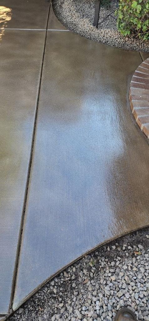 A close up of a concrete walkway with a brick walkway in the background.