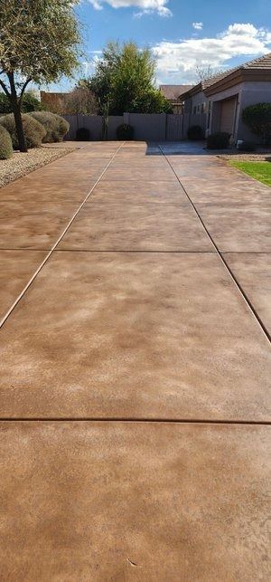 A concrete driveway leading to a house on a sunny day.