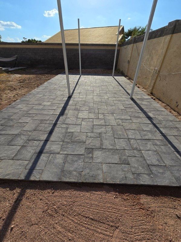 A concrete walkway leading to a house with a fence in the background.