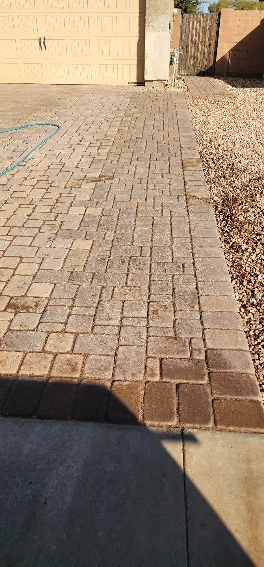 A brick walkway leading to a garage and a driveway.