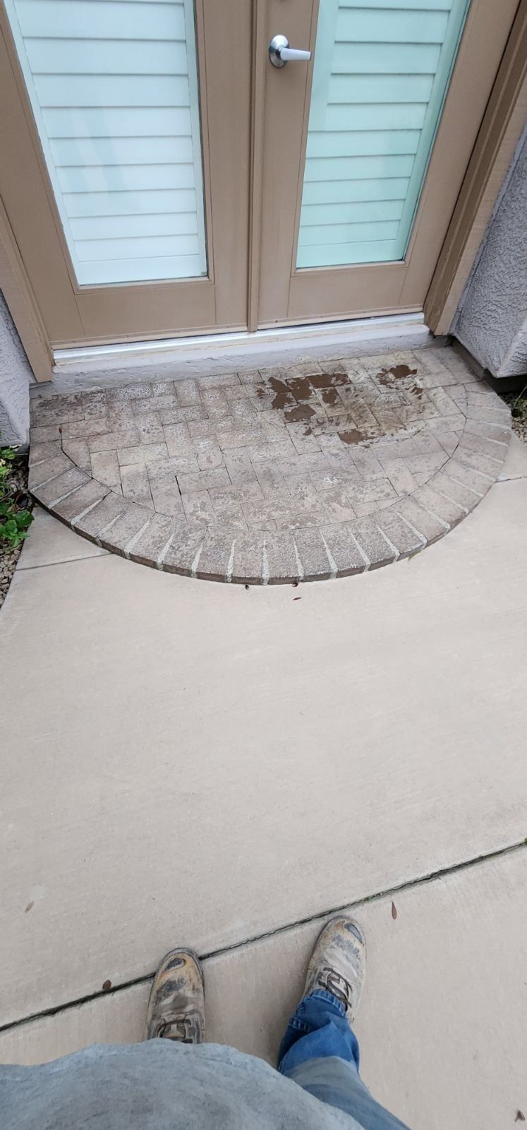 A person is standing on a sidewalk in front of a door.