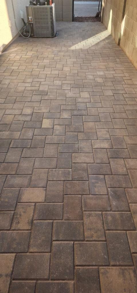 A brick walkway leading to a building with a brick wall in the background.