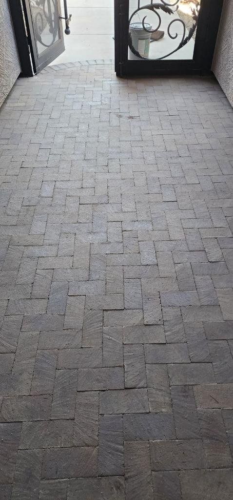 A brick walkway leading to a door with a wrought iron gate.