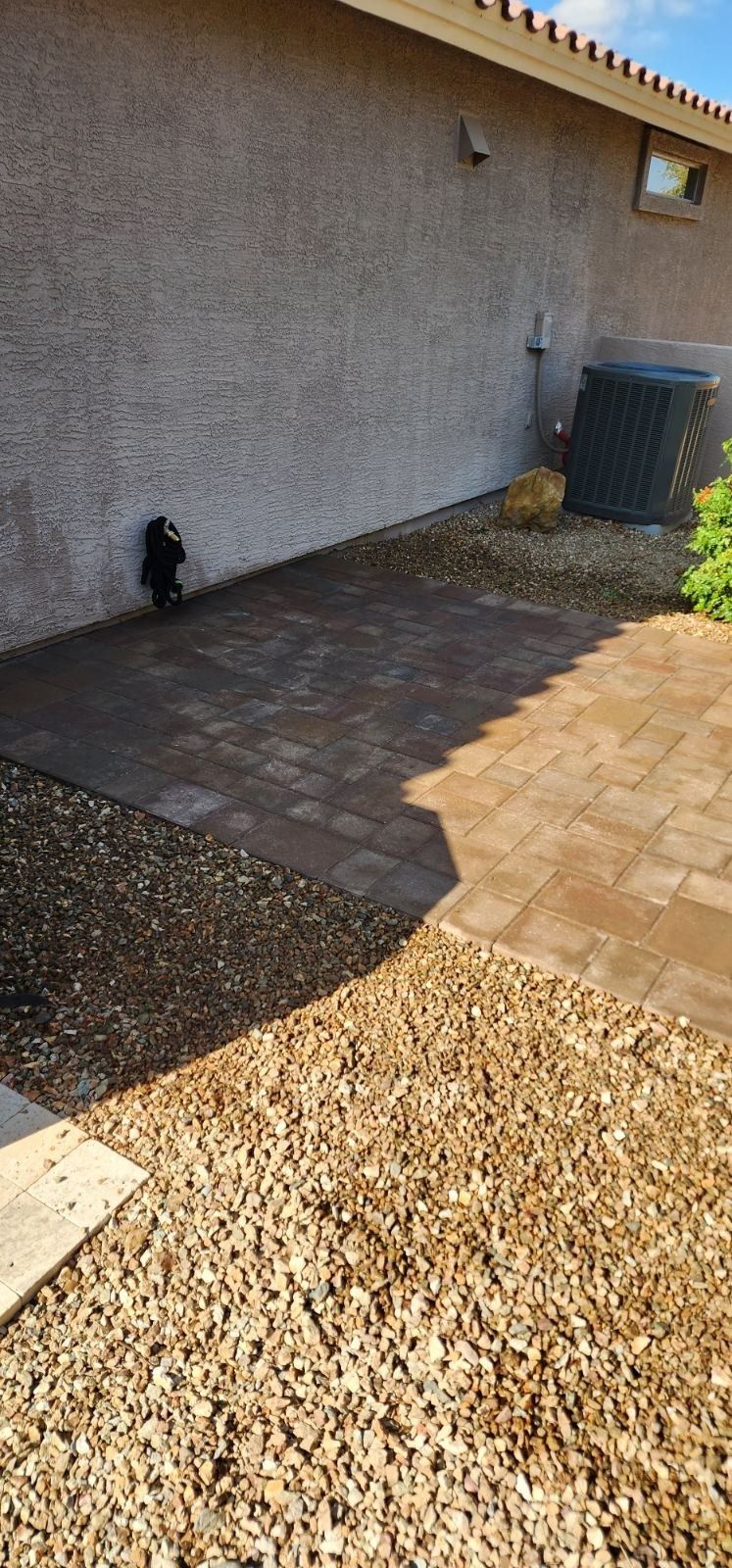 A house with a patio and gravel in front of it.