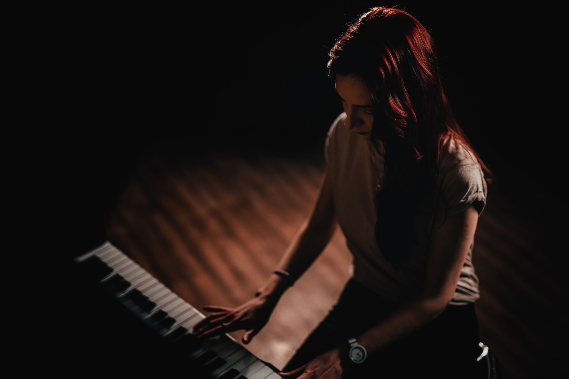 A woman is playing a keyboard in a dark room.