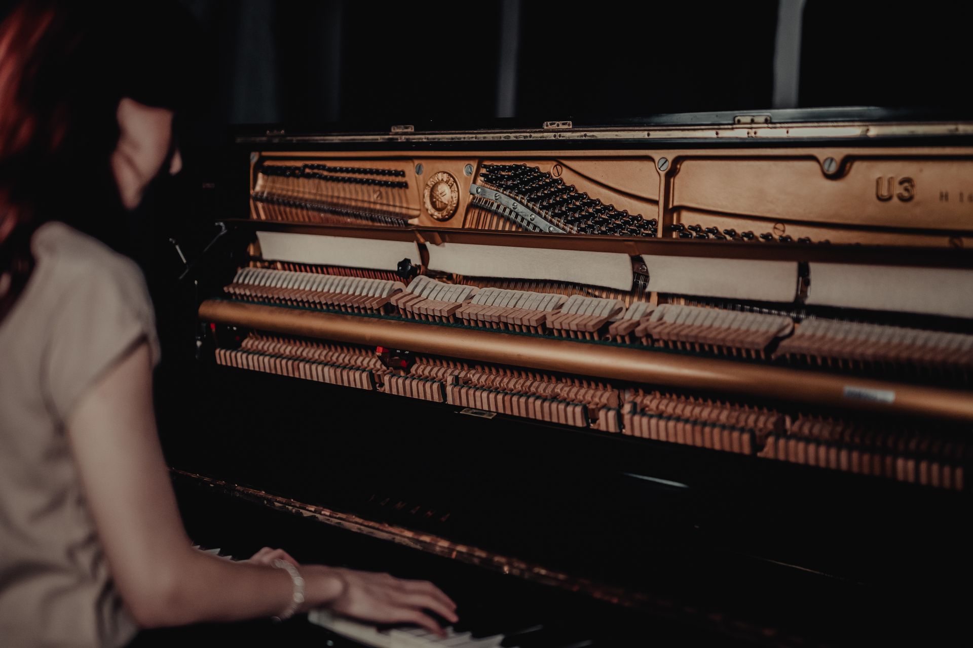 A woman is playing a piano in a dark room.