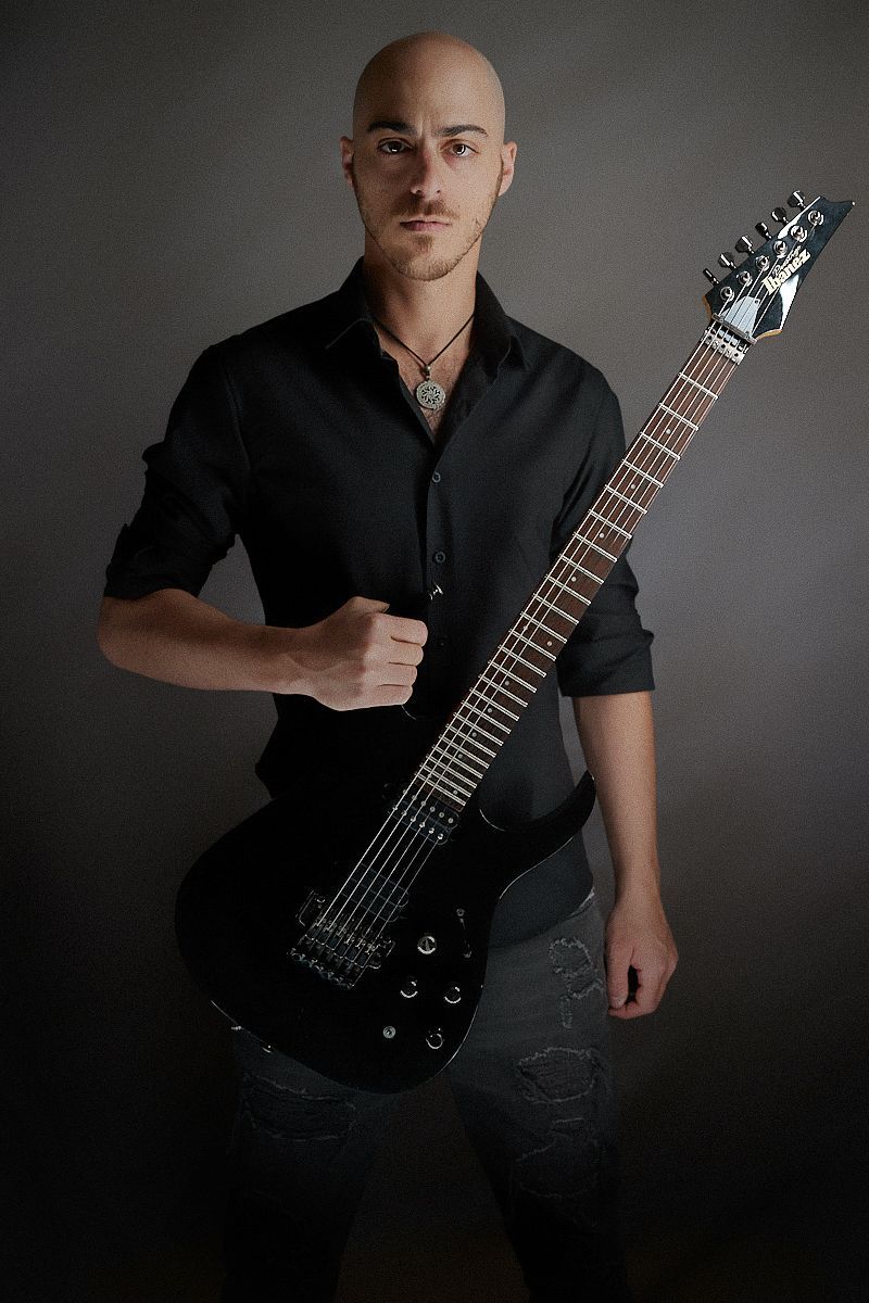 A man in a black shirt is holding a black guitar