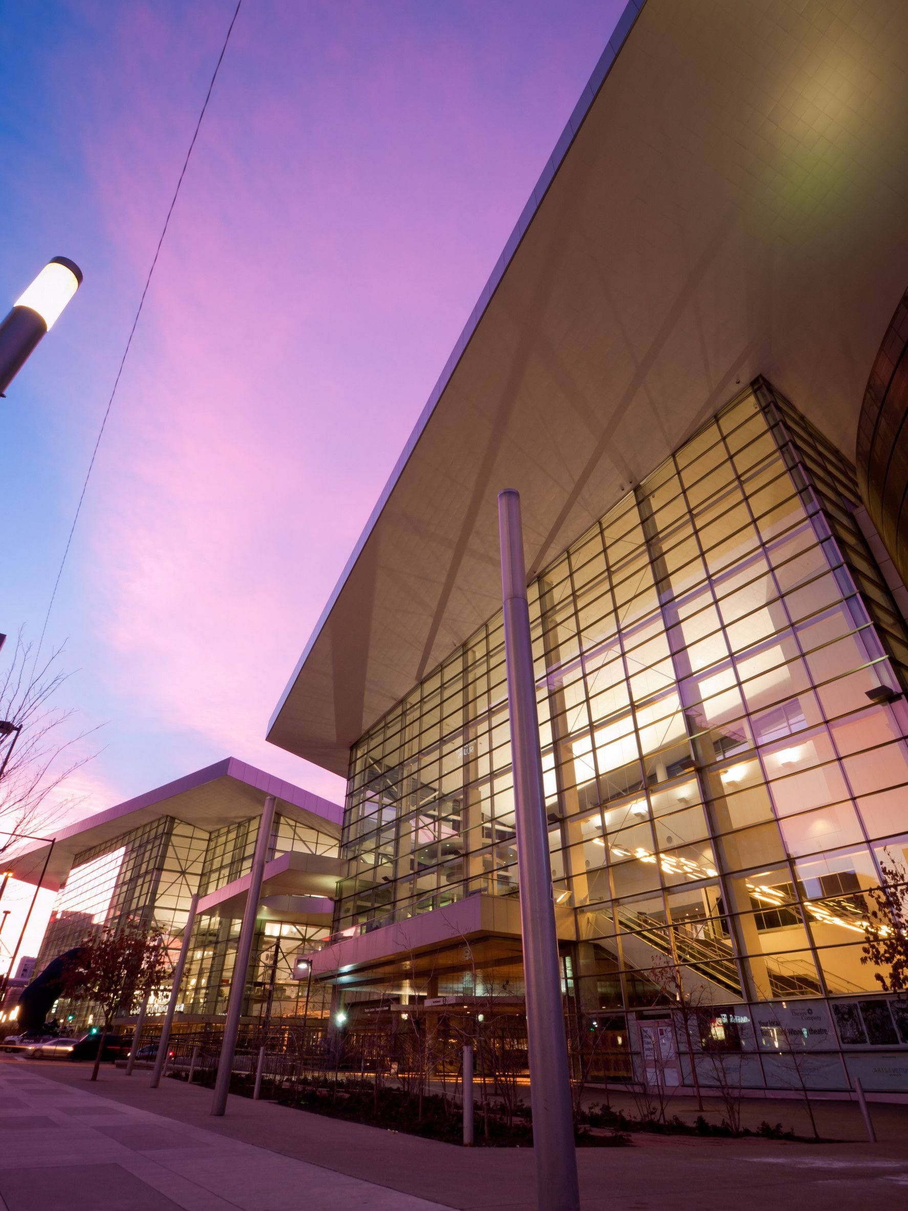 Modern building exterior with glass walls under a purple and pink sunset.