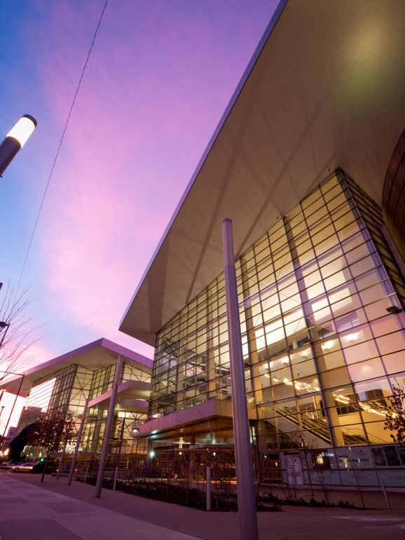 Modern building exterior with glass walls under a purple and pink sunset.