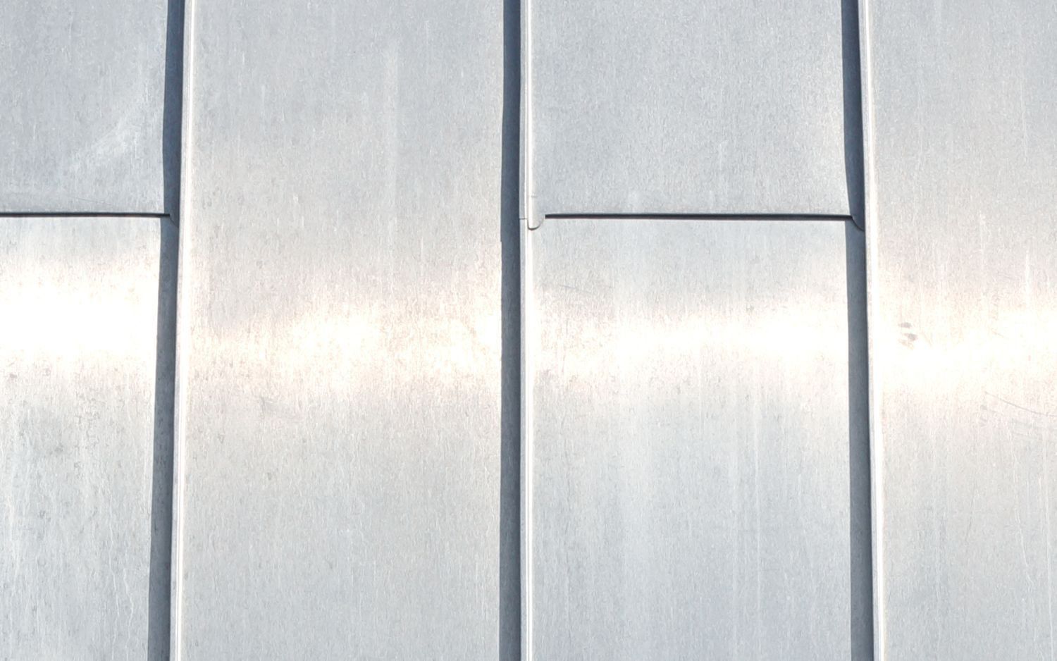 Close-up of a silver, rectangular wall surface with vertical and horizontal seam lines.