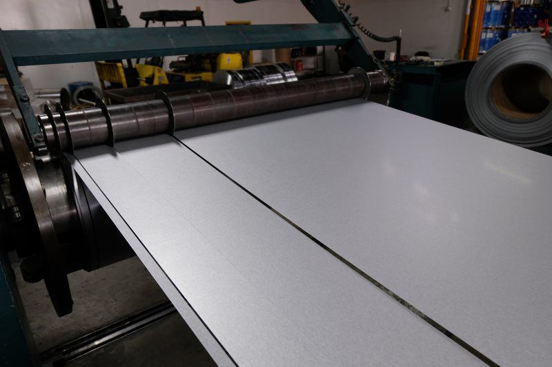 Metal sheet being cut by a machine in a factory setting.