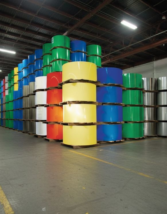 Stacks of colorful metal rolls in a warehouse, including blue, green, yellow, red, and silver.